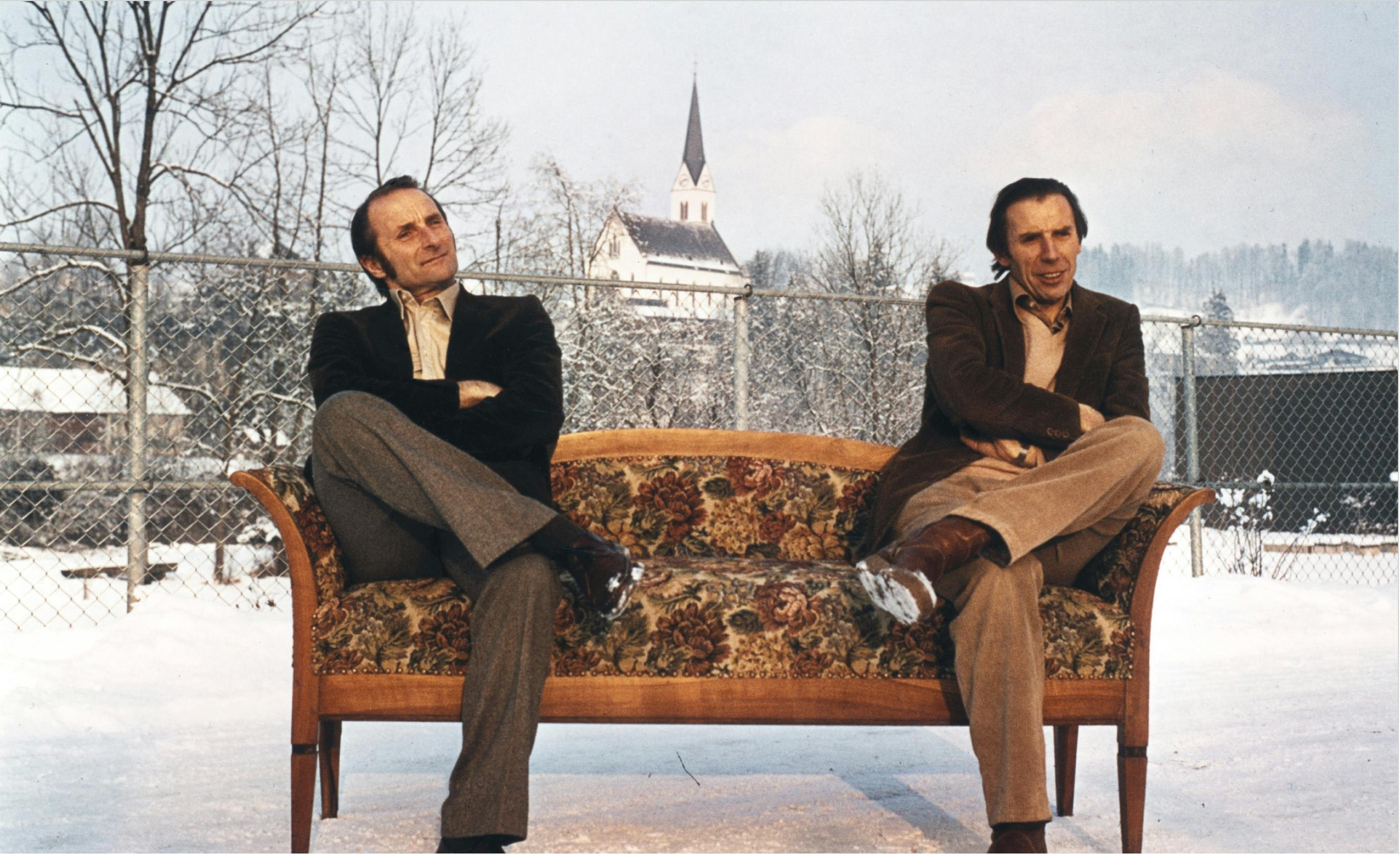 Unternehmensgründer Elmar und Konrad Dorner 1982 bei einem spontanen Fotoshooting vor der Firma auf einem Bregenzerwälder Kanapee mit der Egger Kirche im Hintergrund.